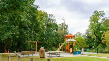 View of playground, swings, bench, and picnic table