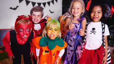 Group of 5 middle-school children in Halloween costumes smiling at camers