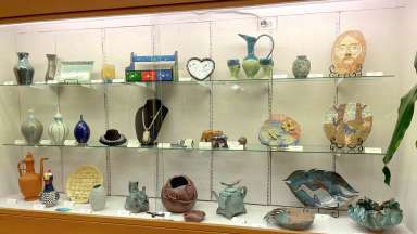 A display case filled with handmade pottery and jewelry pieces