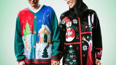 Close-up of two smiling people wearing garish winter-themed sweaters