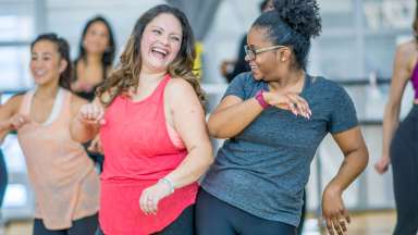 Diverse group of women dancing in Zumba class, smiling at each other
