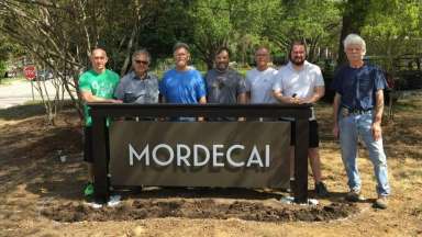 Residents stand behind a new Mordecai neighborhood sign