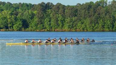Two rowing teams competing on a lake with a forest in the background.