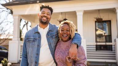 African-American couple smiles in front of house