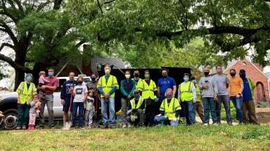 Group of volunteers posing for a picture in front of a dump truck.