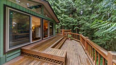 A home with a wooden deck and lush green trees.