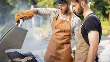 Two men cooking hamburgers on a barbecue grill