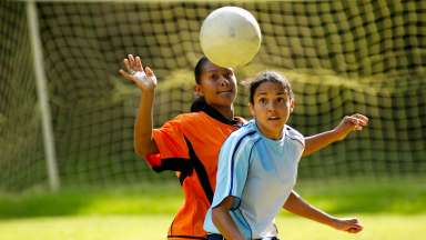 Two soccer girls struggling for the ball.