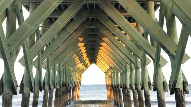 The under of a pier looking out into the ocean.