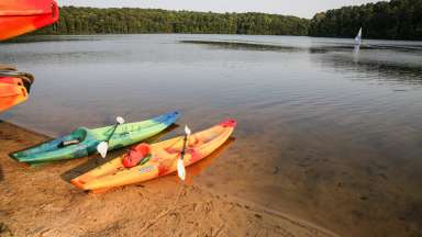 Two kayaks sitting on the beach of a lake.