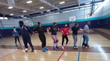 People with arms linked skating in a gymnasium
