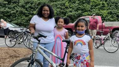 Woman and two young girls standing beside a bicycle