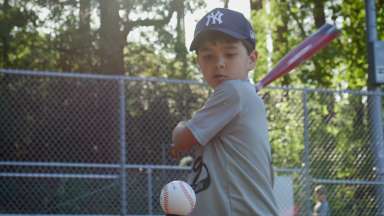 Boy standing at bat getting ready to hit a ball.