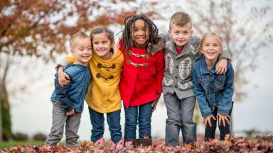 Children standing together smiling in leaves
