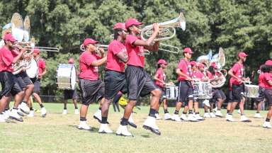 School band in formation wearing red shirts and black shorts