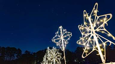 Holiday star lights made out of white plastic hangers light the night sky