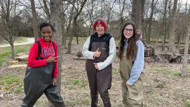 3 youth smiling in outdoor wooded area wearing rubber chest bootfoot waders