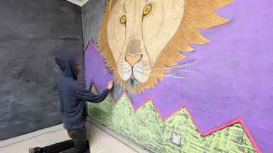 Jabari Harris creates a chalk mural of a lion at Pullen Arts Center