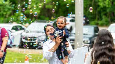 baby being held while playing with bubbles