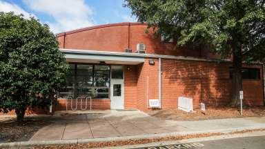 Front of the pioneer building. It is a brick buiding with trees in front of it.