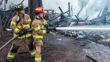 Raleigh fire fighters aim fire hose at destroyed home