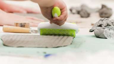 A slab of clay is texturized using a roller