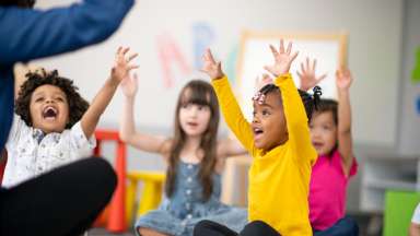 happy children sitting on the floor with their hands in the air