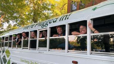 ten students peeking their heads out of the window of a school bus