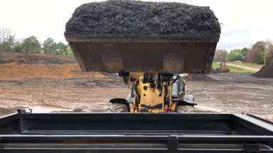 Bulldozer loading yard waste product onto trailer.