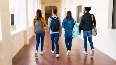 students walking in a hallway wearing backpacks