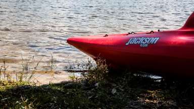 red front end of a kayak on the shoreline