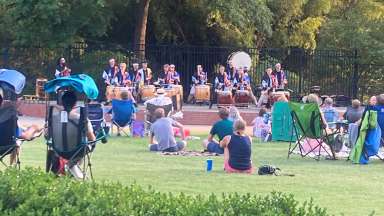 people watching a group perform on the drums outdoors