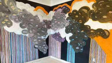 A colorful chalk wall mural featuring clouds and colorful lines by artist Joanna Moody