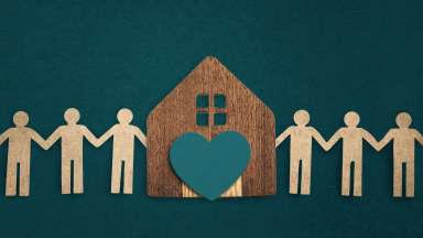 cut out paper of people holding hands with a house and heart in the center
