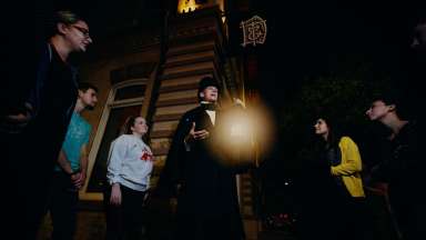 man holding a lantern talking to a group of people