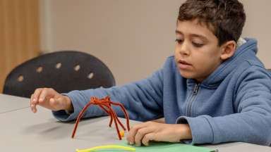 child playing with pipe cleaner crafted spider