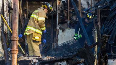 A fire marshal examines a burnt structure.