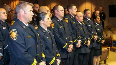 Firefighters in forma uniform stand at ceremony honoring promotions and retirements