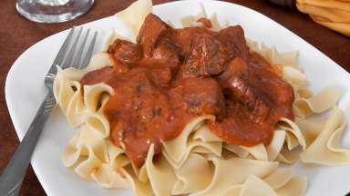 a plate of meat and sauce over noodles