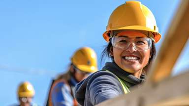 woman working on a construction site, construction hard hat and work vest, smiling