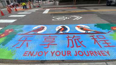 Artwork stating "enjoy your journey" is placed on a Raleigh curb extension