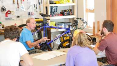 an instructor sitting while teaching about a nearby bike