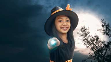 a young witch in front of a full moon pointing a magic wand