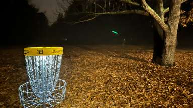 illuminated disc golf basket in the forest