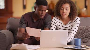 young couple review bills and looking at a laptop