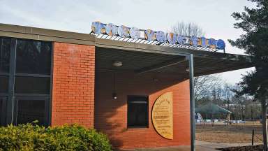 A blue and beige sign that says &quot;Take Your Time&quot; mounted over the entrance to Green Road Park