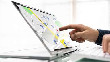 A map on a computer screen and a person pointing at a location on the map