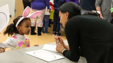 a child with bunny ear headband talking to an adult