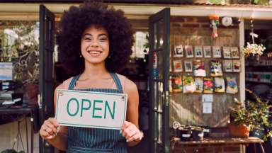 Woman holding open sign for small business garden