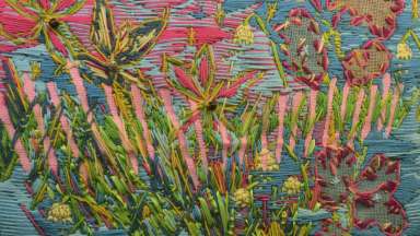 Artwork made with fibers and yarn creating flowers with bright pastel colors.